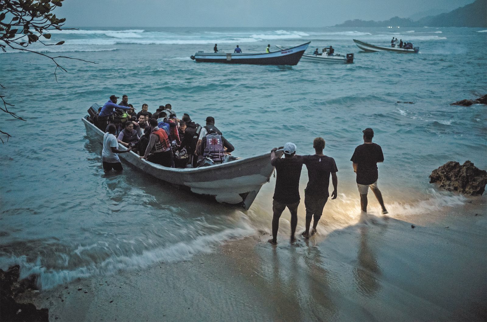 DOS: Un bote clandestino con migrantes afganos, chinos, venezolanos y ecuatorianos parte en la noche desde Capurganá para transportarlos hasta Carreto, en Panamá, desde donde tendrán que caminar la selva del Darién: una travesía para intentar llegar hasta Estados Unidos. Foto: Federico Ríos.