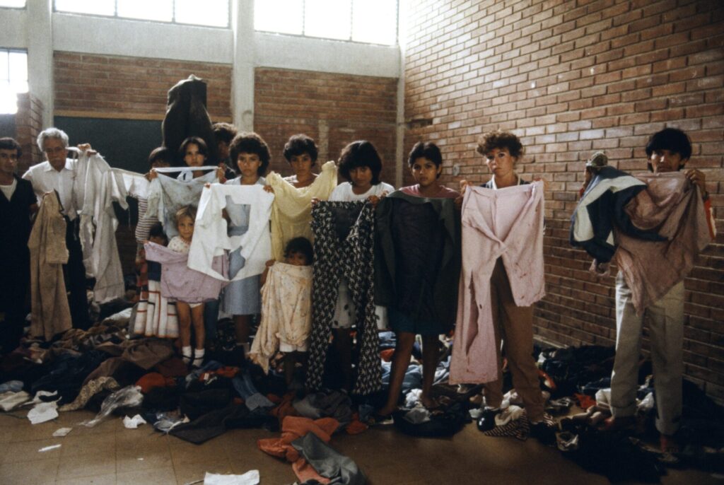 Mujeres, hombres y niños, exhiben la ayuda en prendas que les llegaron. La respuesta bien intencionada de todo el mundo frente a la tragedia, llega meses más tarde, convertida en toneladas de vestidos usados o para invierno.