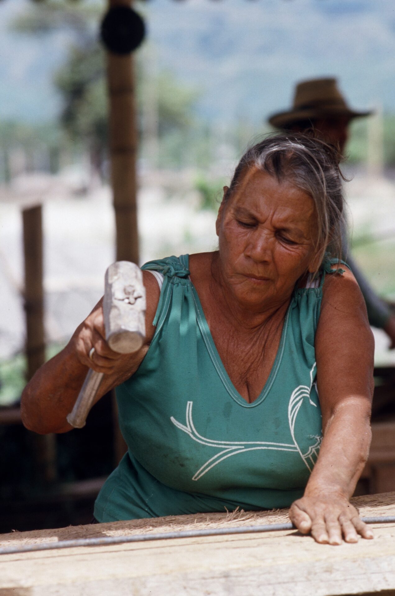 Una mujer armerita de la tercera edad martilla "canastas" para construir las columnas que soportarán las estructuras de 120 casas.