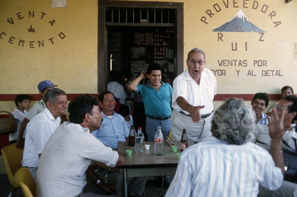 "Y seré santofimista hasta la muerte" grupo de hombres debatiendo en una tienda.