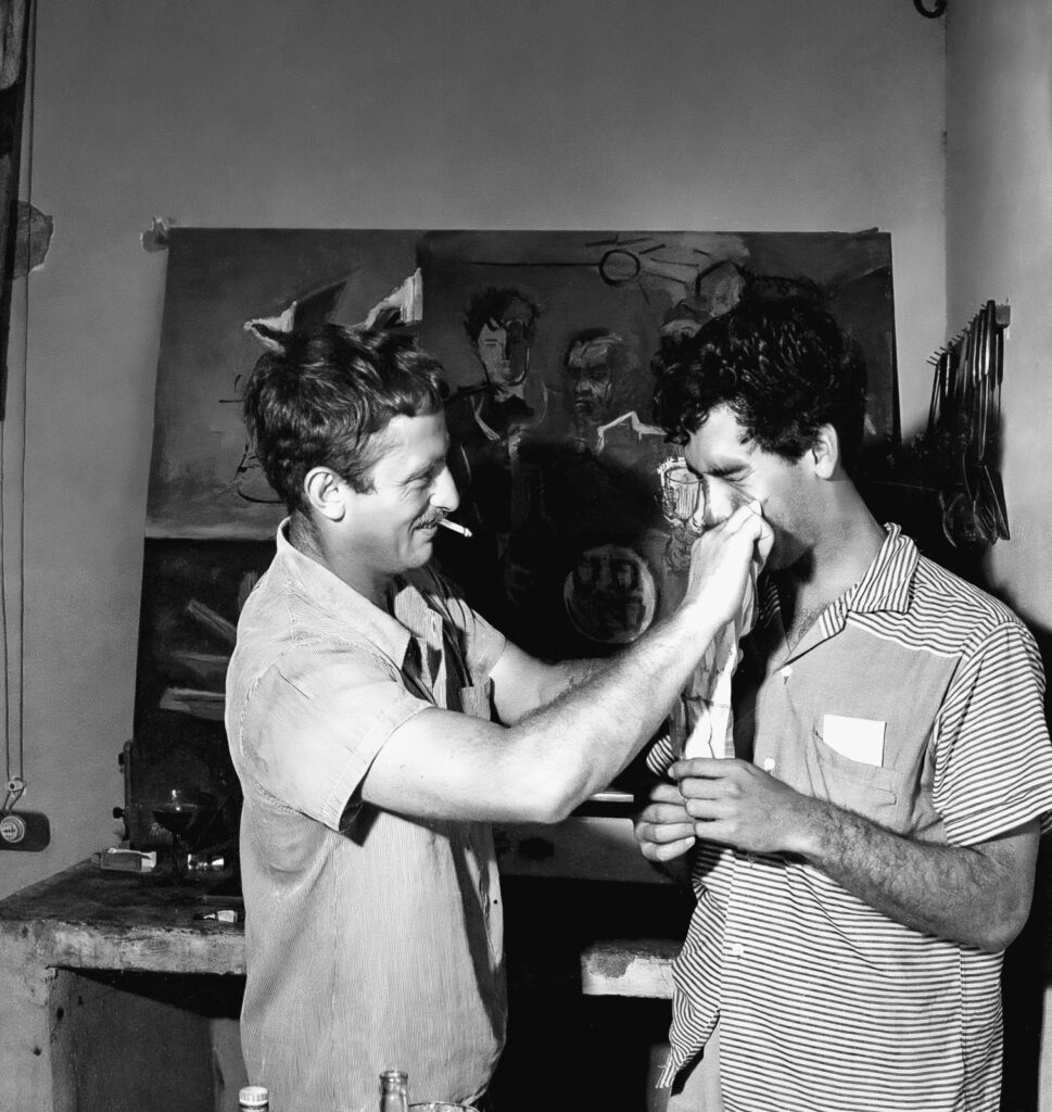 En 1955, en Barranquilla, Juan Antonio Roda retrató a cinco miembros de La Cueva: Alfonso Fuenmayor, Nereo López, Eduardo Vilá, Álvaro Cepeda Samudio y Alejandro Obregón. Con motivo de la instalación del cuadro en el bar, Cecilia Porras realizó un happening que fue fotografiado por Nereo López. Foto de la Biblioteca Nacional de Colombia.