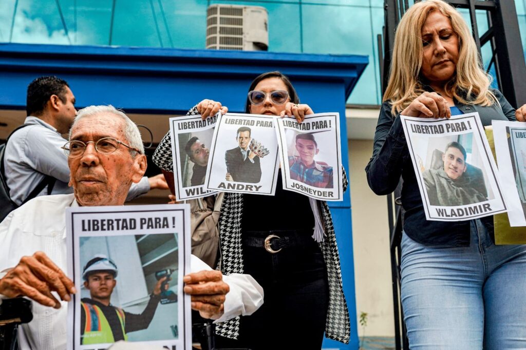 Familiares de migrantes venezolanos deportados a El Salvador muestran fotografías de sus allegados mientras solicitan permiso para visitarlos en el CECOT, 10 de junio de 2025. © SOPA Images Limited / Alamy Live News
